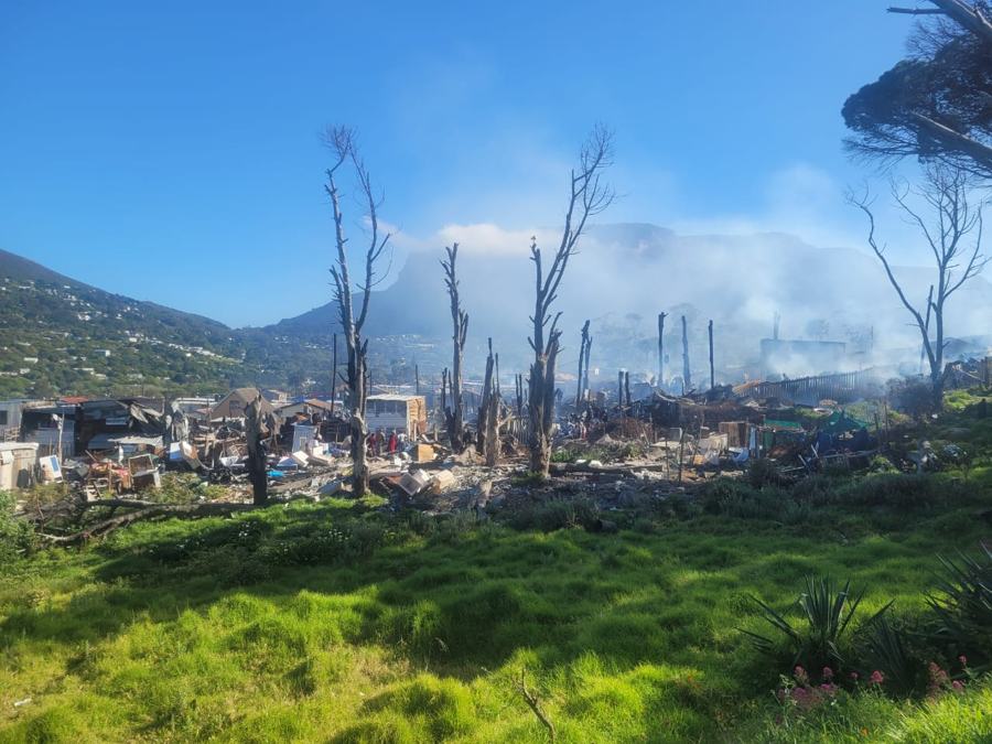 Burnt trees and ruins on the hillside, smoke still rising