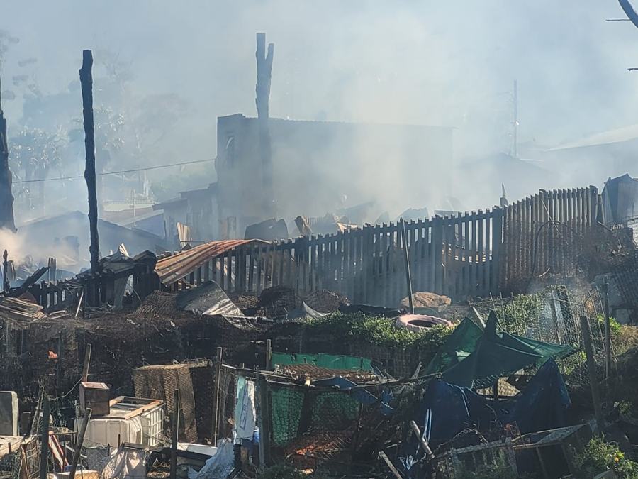 Smoke over a fence and burnt homes